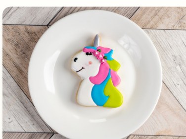 Rainbow unicorn sugar cookie on a white plate