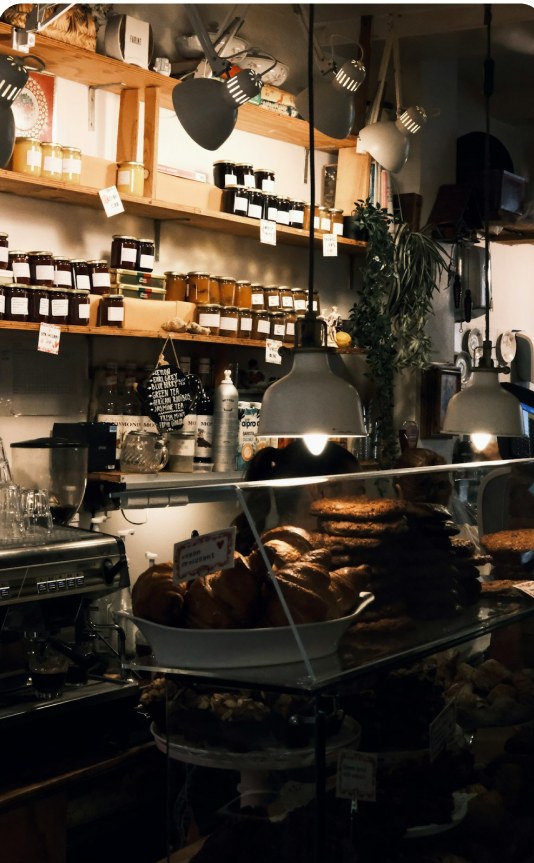 A warmly lit bakery kitchen with shelves of jars and pendant lamps